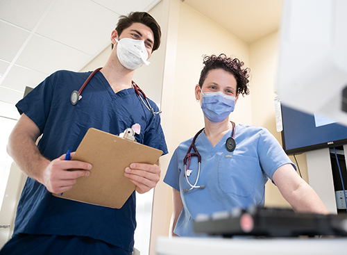 Medium shot of two health professionals seen behind electronic equipment