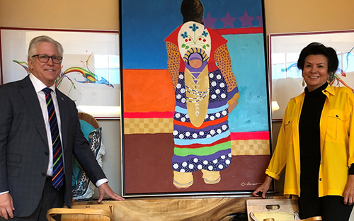 Two signatories to the agreement in front of an Aboriginal painting