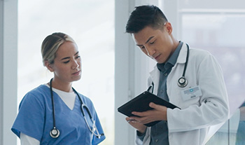 Average shot of two healthcare professionals chatting in front of an ipad