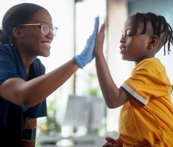 Health professional giving a high five to a young boy.