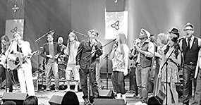 Musiciens performant sur une scène entourée de drapeaux franco-ontariens